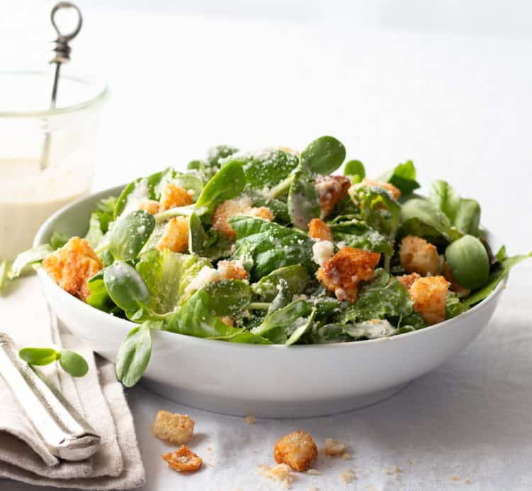 A salad in a white bowl on a white tablecloth